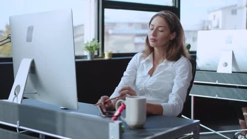 A Focused Woman Works Diligently at Her Computer in a Stylish Modern Office Space
