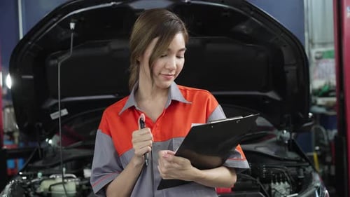 Asian woman office employee holding clipboard standing at auto repair shop