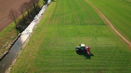 Combine tractor working fertilizing on green field in spring