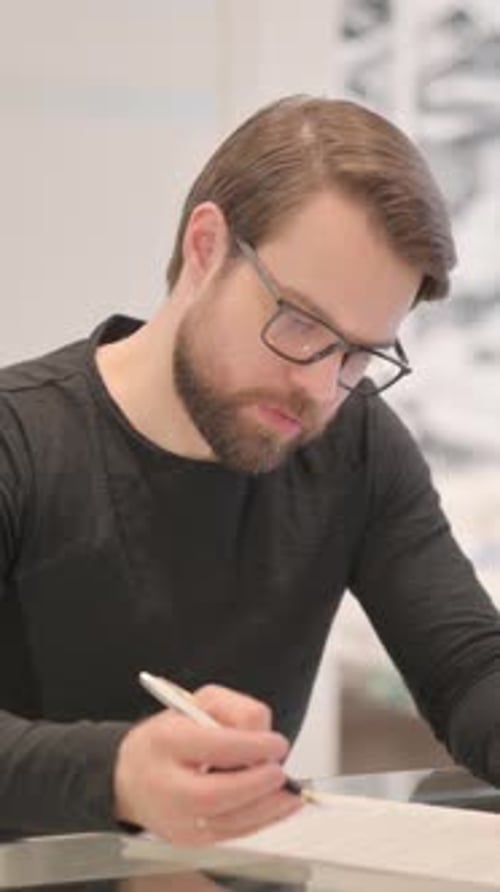 Man Filling Out Paperwork with a Pen Indoors