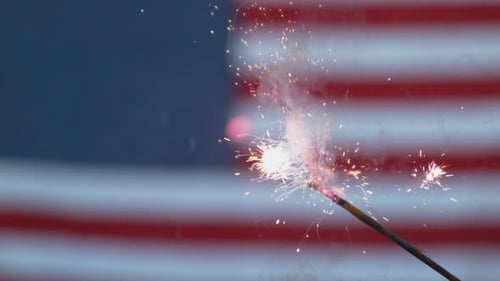 Sparkler Burning Brightly with American Flag in Background