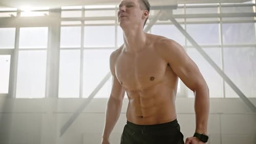 Confident Male Athlete Wiping Off Sweat When Exhausted Resting After Intense Workout in Smokey Gym