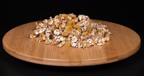 Dried Chamomile Flowers Rotating on Wooden Board