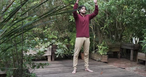 Focused caucasian man practicing yoga meditation on terrace in nature, copy space, slow motion