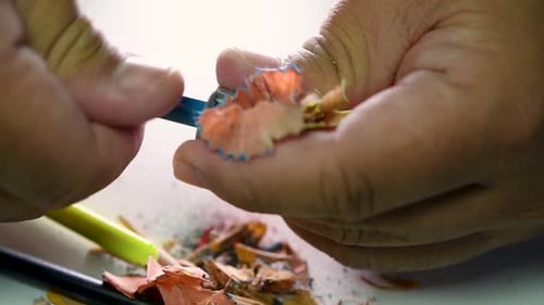 Footage of hands slowly sharpening a pencil and some coloured pencils with a Wedge Pencil Sharpener.