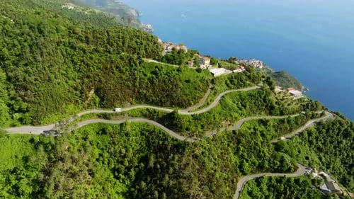 Panoramic drone shot of a camper driving on a winding road in Cinque Terre, Italy
