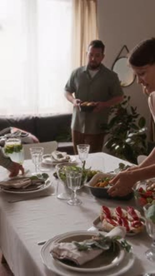 Family gathers around dining table setting out food