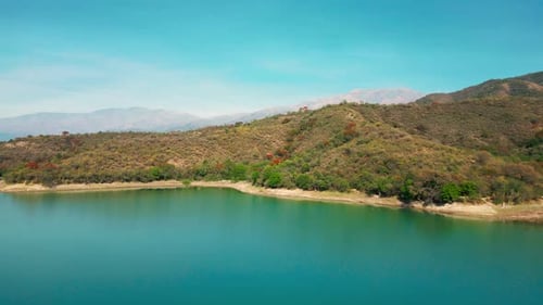 Aerial drone flying over a blue water lake with mountains landscape