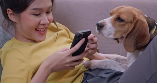 Woman Relaxing on Couch with Dog, Using Smartphone