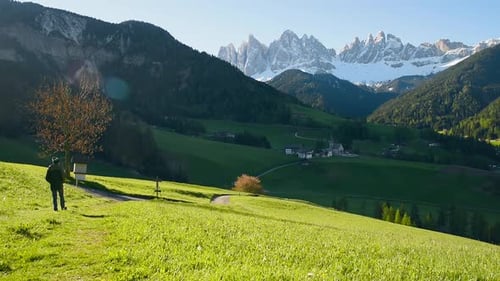 Man Traveler Walking Along the Path Towards Santa Maddalena Village and Looking at Pointer in
