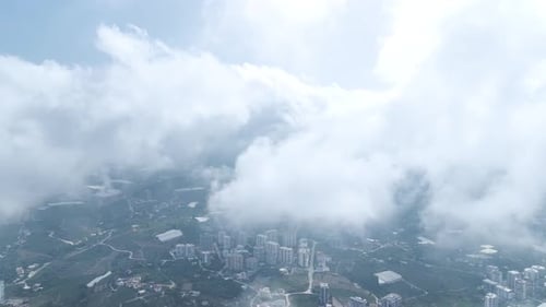Aerial View Gliding Over Clouds with a View of the City Beneath