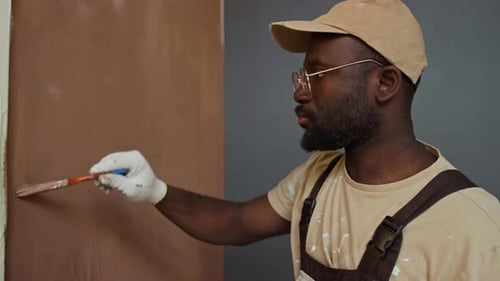 Man Applies Brown Paint to Wall with Brush