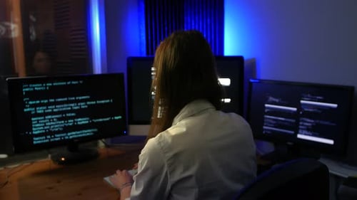 Female computer programmer programming code at night in a dark office