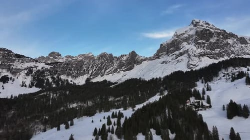 Drone approaching Fronalpstock mountain in Glarus Nord, Switzerland. Abundant snow on a winter day.