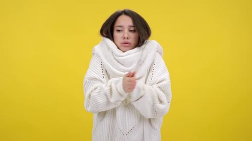 Une femme brune frissonne de froid et respire sur les paumes