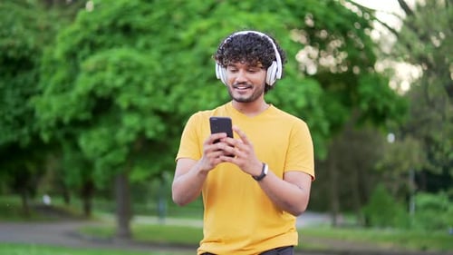 Man Walking in Park Using Mobile Phone