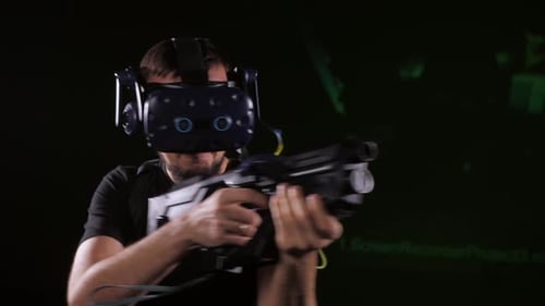 Un jugador masculino con gafas de realidad virtual sobre un fondo negro está jugando una realidad virtual