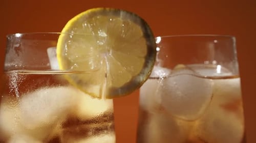 Rotating Iced Tea in a Glass with Ice Cubes on an Orange Background
