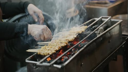 Street Food Vendor Grills Traditional Pork Satay Skewers Over a Charcoal Fire at a Night Market in