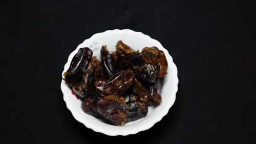 fresh dates in ceramic bowl studio shot of on black background