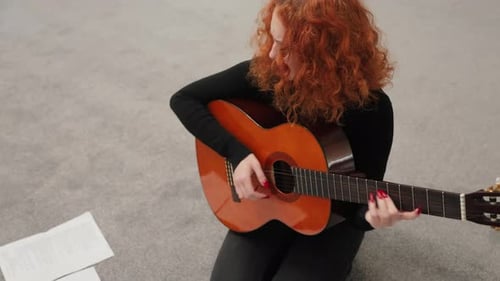 Woman With Red Hair Plays Guitar and Sings