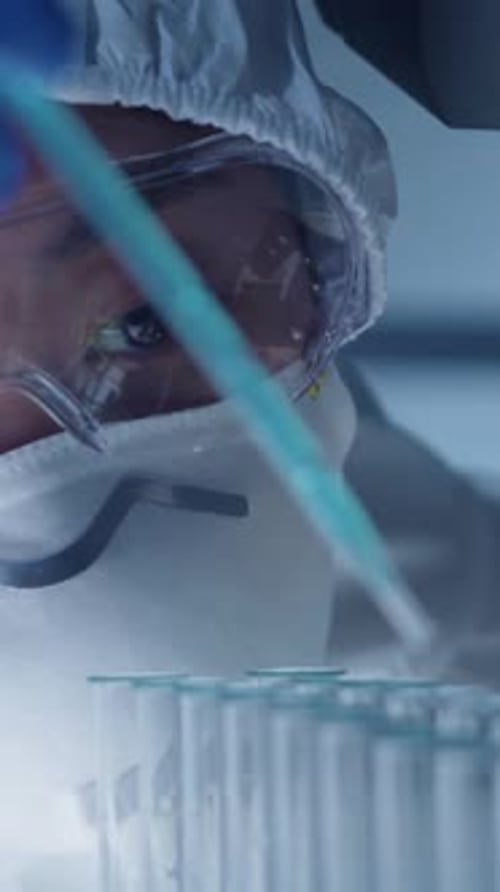Close-up of Young Female Chemist Dripping Blue Substance into Sample Tubes