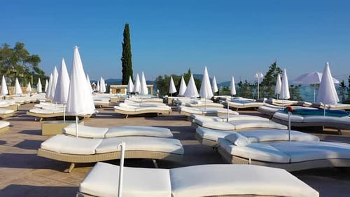 Close up tracking shot of a hotel terrace with pool and sun beds.