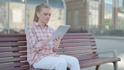 Woman Using Tablet Device on a Park Bench