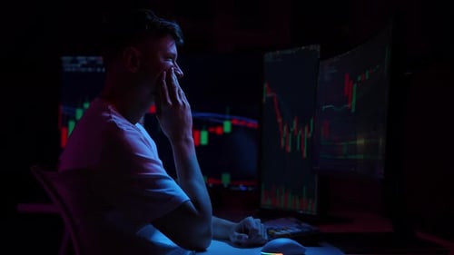 Stressed Crypto Trader Touching Head with Hands While Looking at Multiple Computer Monitors Showing
