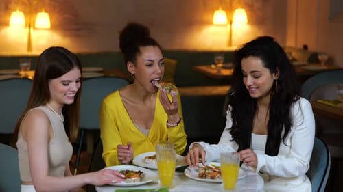 Smiling Young Ladies Having Dinner in a Restaurant and Biting Bruschettas Meeting of Friends
