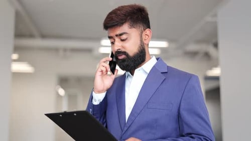 Young Adult Businessman Talking on Phone in Office