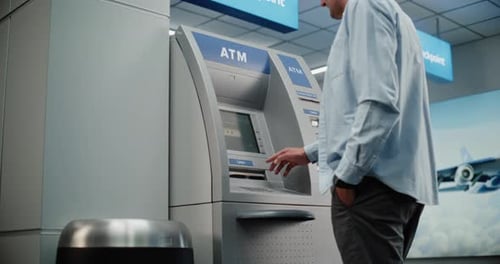 Airport Terminal Man Pressing Buttons on ATM Keypad Entering PIN Code Withdrawing Cash Taking Money