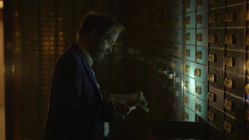 Man Counting Money in Bank Vault at Night
