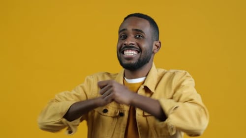 Enthusiastic Man Dancing Joyfully on Yellow Background