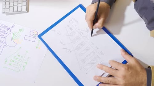 Male hand in suit drawing financial statement on paper on office desk.