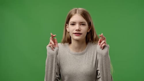 Young Adult Crossing Fingers on Green Background