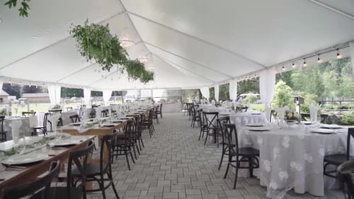 Elegant banquet reception for a luxurious outdoor wedding. Many tables and much opulence.