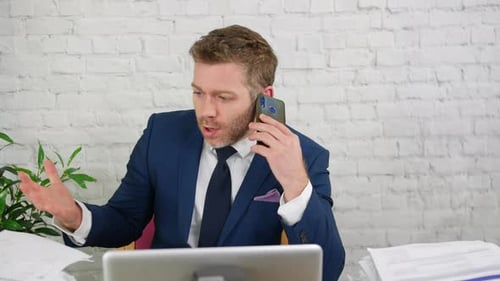 Man Talking on Phone at Desk in Office