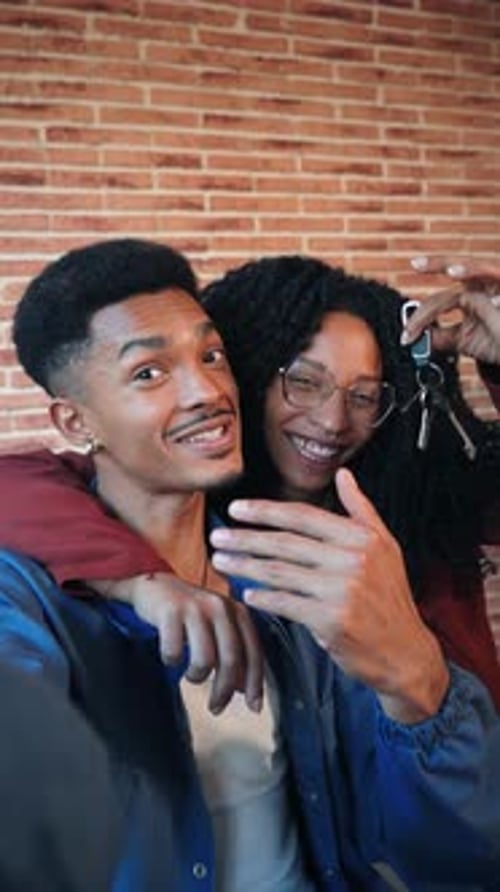 Un couple joyeux célébrant leur nouvelle maison tout en exhibant leurs clés de manière ludique avec des sourires éclatants