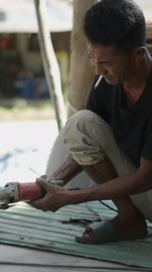 Man Grinding Metal Rod Outdoors