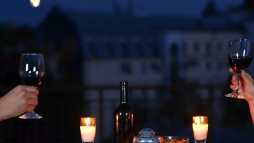 Happy Couple Clinking Glasses with Wine While Having Date on the Terrace Outdoors in the Evening