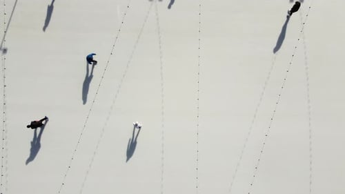 Die Leute fahren auf der weißen Eisbahn auf der Straße und werfen lange Schatten