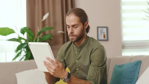 Man Using Tablet at Home on Sofa