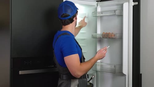 Repairman Inspecting Refrigerator with Tablet Computer
