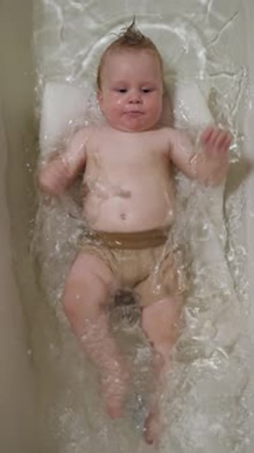Adorable Infant Splashing in Water in Bathtub