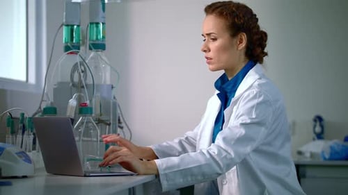 Woman Scientist Types on Laptop in Laboratory
