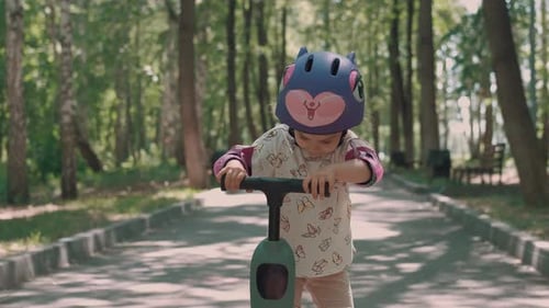 Girl 3 Years Old Rides a Scooter in Protective Clothing