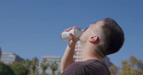 Close-up of a young Caucasian man drinking an isotonic drink on break from playing on a city street