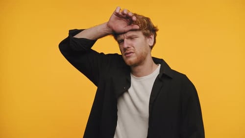 Tired Man Wipes Sweat off Brow on Orange