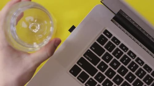 Top view of hands rising glass of water, drinking water daily, laptop keyboard work writing, hydrate